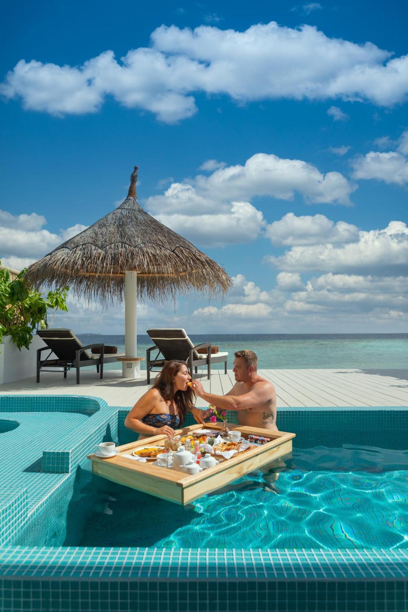 Malahini Kuda Bandos Resort Hulhumale Bagian luar foto A couple dining at the pool of a resort in Maldives